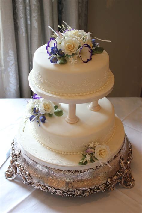 a two tier cake with pillars and icing flowers to create this beautiful finish by inspire