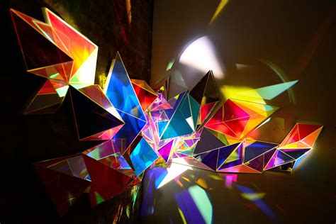 An Abstract Sculpture Made Up Of Many Different Colored Shapes And Sizes With The Light Shining