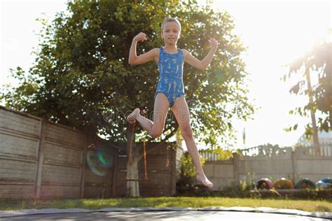 Little Sports Girl Jumps On A Trampoline Outdoor Shot Of Girl Jumping On Trampoline Enjoys