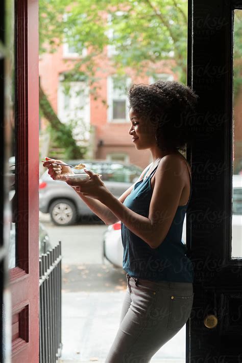woman eating cereal leaning against open front door by stocksy contributor jamie grill atlas