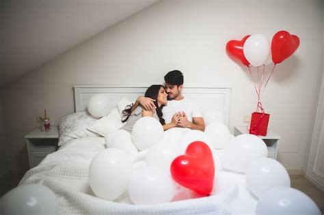 Free Photo Couple Embracing In Bed Surrounded By Balloons