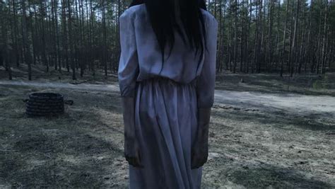 Girl With Long Black Hair In Image Of Scary Ghost Zombie Stands Near Stone Well Among Forest