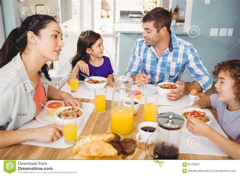Familia Feliz Que Habla Mientras Que Desayunando Imagen De Archivo