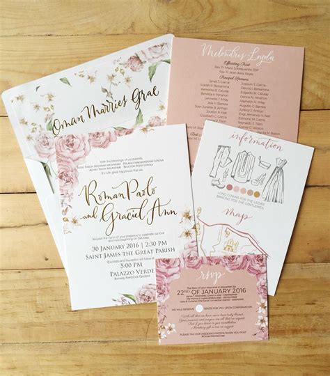 wedding stationery with pink flowers and gold lettering on wood