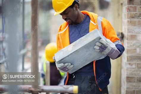 Construction Worker Carrying Brick At Construction Site Superstock