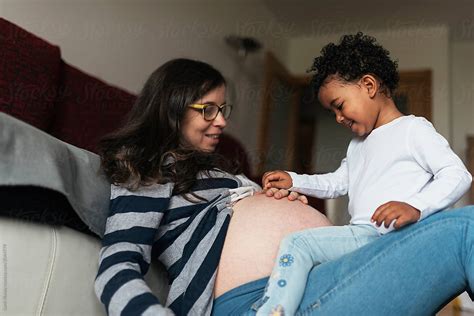 beautiful mixed race girl playing with pregnant mother s belly by stocksy contributor santi