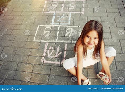 Beautiful Cheerful Little Girl Playing Hopscotch On Playground Stock