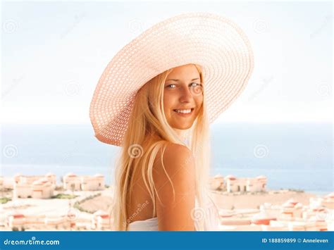 Woman With Blond Hair Wearing Hat Enjoying Seaside And Beach Lifestyle In Summertime Holiday