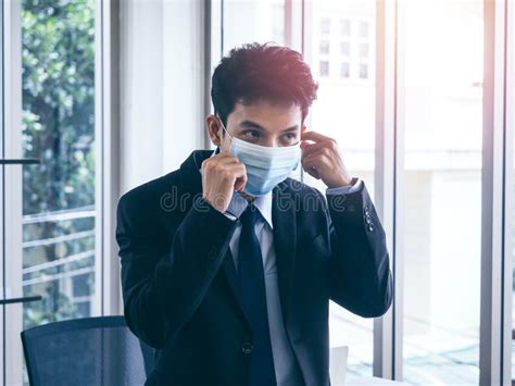 Young Asian Businessman In Suit Wearing Medical Face Mask In Office