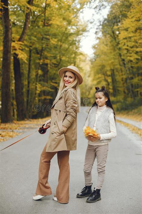 Mother And Her Daughter Walking In The Autumn Park Together Stock Photo