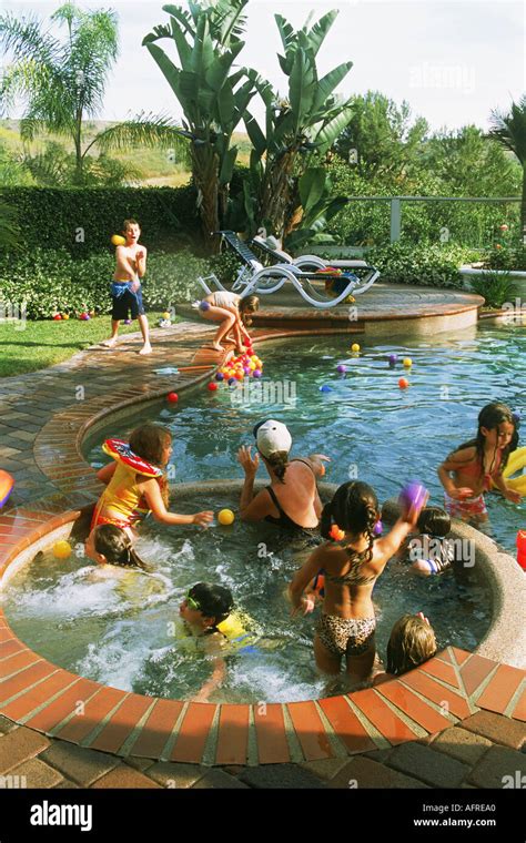 Kids Playing In Backyard Swimming Pool During Birthday Party In