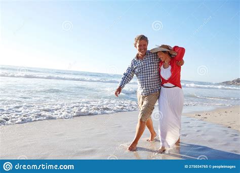 theyre hopeless romantics a mature couple enjoying a late afternoon walk on the beach stock