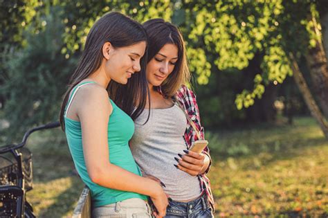 Two Beautiful Teenage Girls Using Smart Phone In The Nature Stock Photo