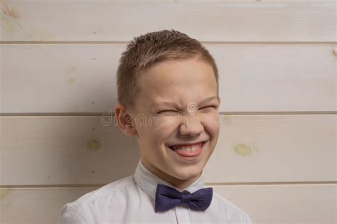 A Boy Of 10 Years Old Is Smiling On The Background Of A Wooden Wall