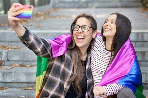pareja de lesbianas feliz alegre sosteniendo la bandera lgbt tomando un selfie al aire libre