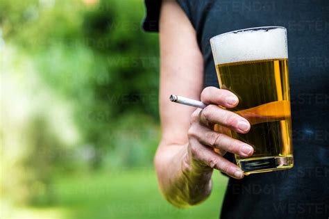 Midsection Of Woman Having Beer While Smoking Cigarette Outdoors Stock