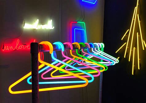 Neon Signs Are Hanging On The Wall Next To A Rack With Clothes Pins In It