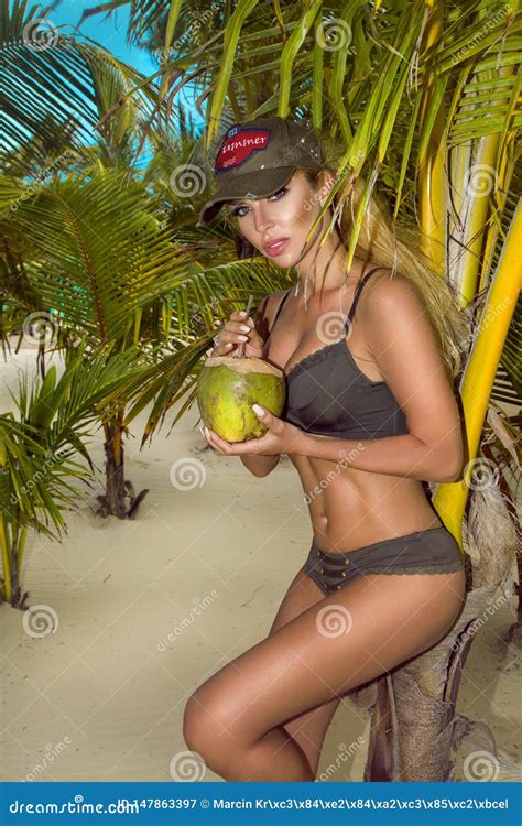 Beautiful Girl In Bikini Posing On The Caribbean Beach And Holding A Coconut Stock Image