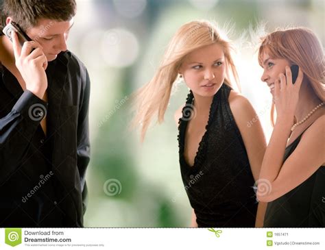 Young Man Speaking By Mobile Phone And Two Women Looking