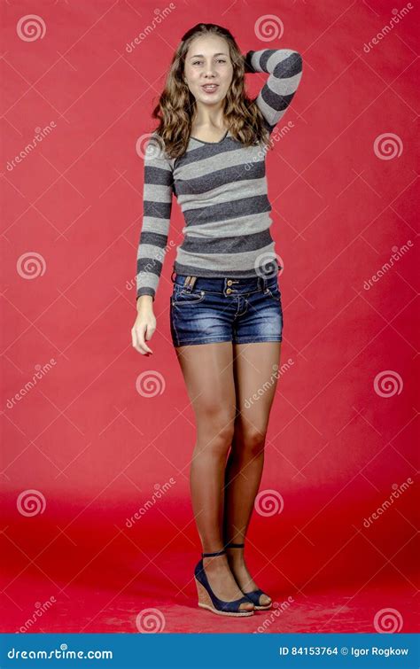 Young Cheerful Girl In Denim Shorts And A Striped Sweater Walking In