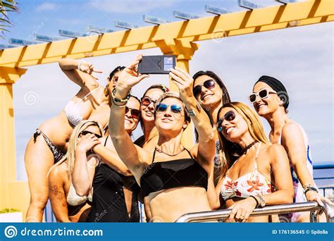 Group Of Happy And Cheerful Young Caucasian Women Have Fun Together In Friendship Taking Selfie