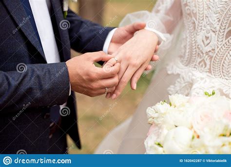 Groom Wears Bride A Wedding Ring Bride Hand Holds A Beautiful Wedding