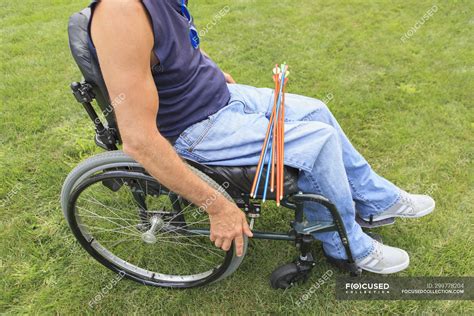 Man With Spinal Cord Injury In Wheelchair Preparing For Archery