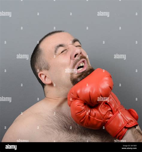 Portrait Of Funny Fat Boxer Getting Punch In Face Against Gray