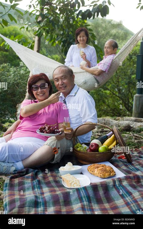 Mature Woman Feeding A Grape To A Senior Man At A Picnic Stock Photo