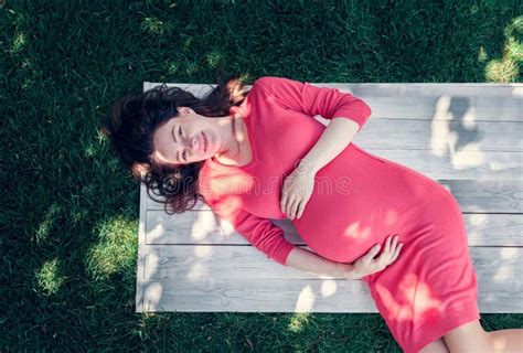Pregnant Girl Dressed In Pink Dress Holds Herself Tummy Stock Image