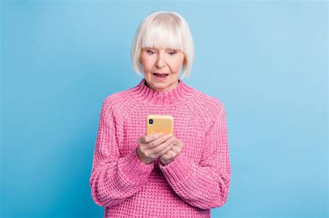 Photo Portrait Of Upset Unhappy Old Woman Holding Phone In Two Hands