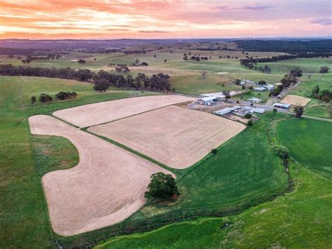 Image Of Aerial View Of Ploughed Paddocks Near Farm Buildings At Sunset