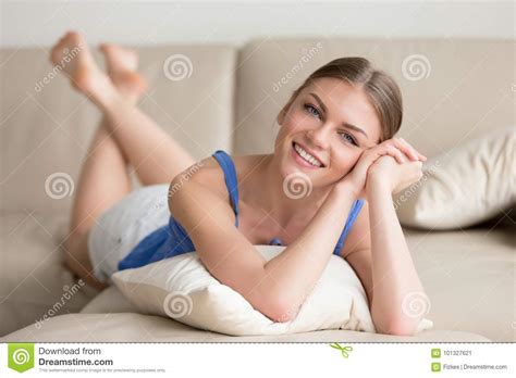 Young Smiling Attractive Woman Lying On Sofa Looking At Camera Stock