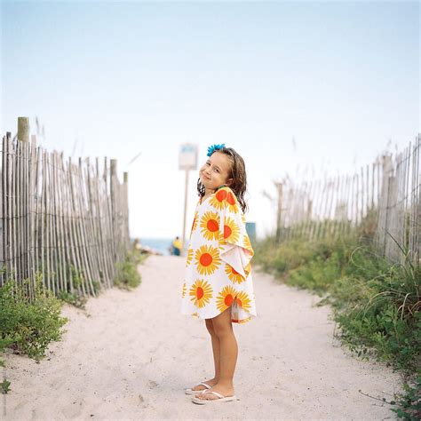 Cute Young Girl Standing On A Beach Walkway With A Cover Up Del Colaborador De Stocksy Jakob