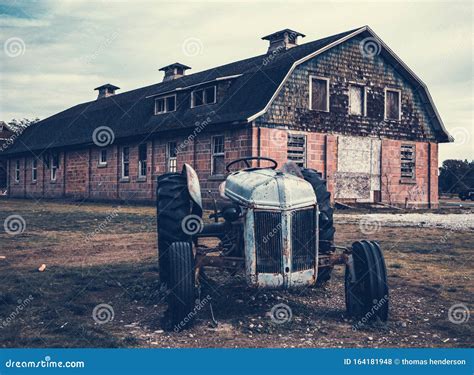 A Very Old Barn With A Old Antique Tractor In Front Stock Photo