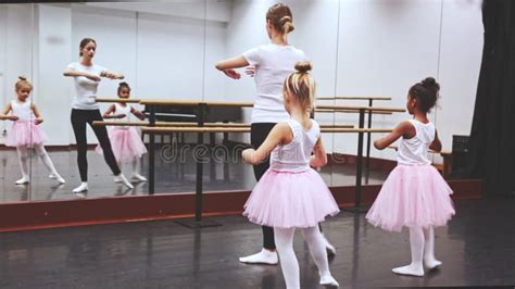 Female Ballet Teacher Demonstrating Choreographic Element To Two Little