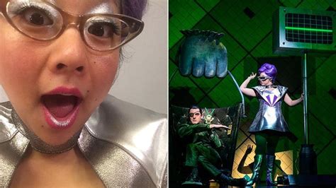 A Woman With Purple Hair And Glasses Making A Funny Face Next To An