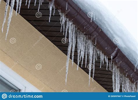 Big Icicles On The Roof Of A Townhouse Roof Of Home Covered With