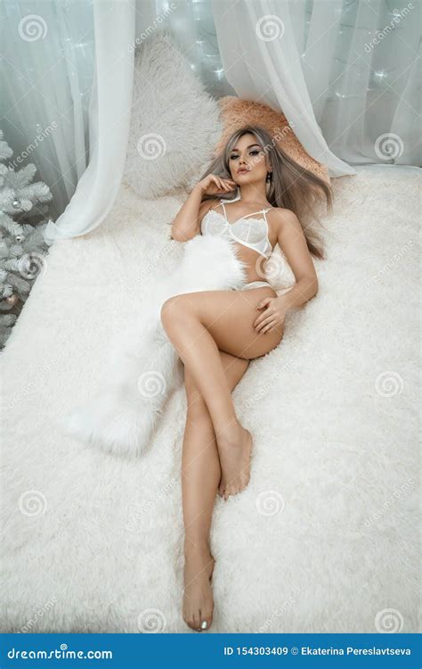 Сексуальная блондинка на кровати в белом женском белье Стоковое Изображение изображение