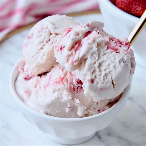Line an 8 x 8 dish with parchment paper. Scoops of strawberry ice cream in white bowl with gold ...