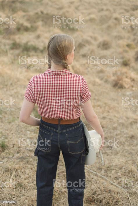 Retro 1950s Cowgirl With White Hat In Red Checkered Shirt And Blue