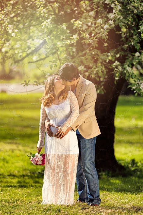 Expecting Couple Kissing Under Tree ~ People Photos ~ Creative Market