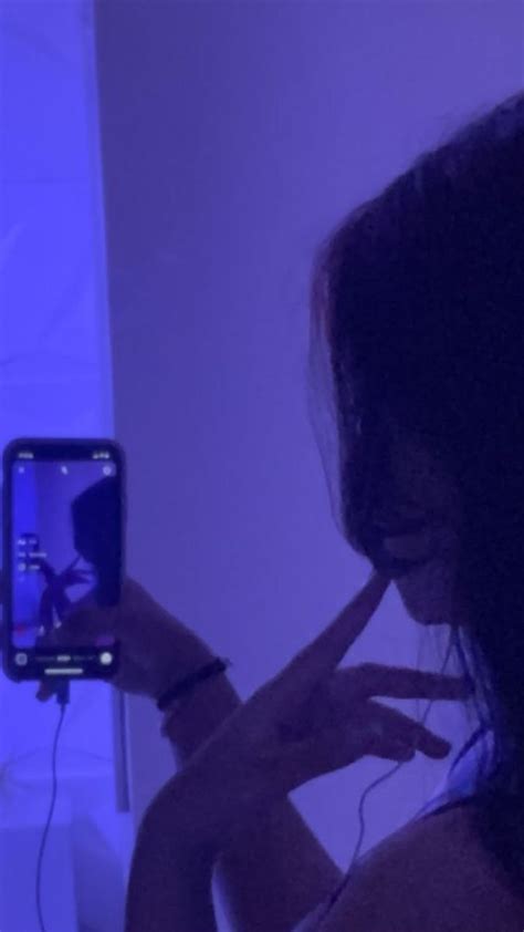 a woman holding up her cell phone to take a selfie in front of the mirror