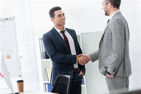 Professional Businessman In Formal Wear Shaking Hands And Smiling Each Other In Office Stock