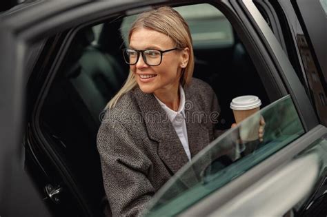 Attractive Businesswoman Wearing Eyeglasses With Takeaway Coffee Getting Out Of Car Stock Image