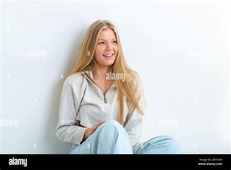 Portrait Of A 19 Year Old Blonde Woman Leaning Against A White Background Looking Away Stock