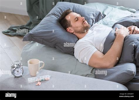 Man Sleeps In Bed After Taking Sleeping Pills In Bedroom Stock Photo