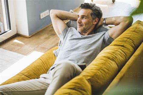 Man Looking Away While Relaxing On Sofa At Home Stock Photo