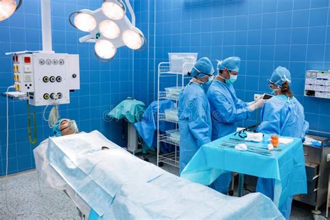 Surgeons Using Digital Tablet And Patient Lying On Operation Bed Stock