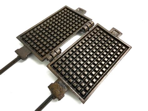 Two Waffle Irons Sitting Next To Each Other On Top Of A White Surface